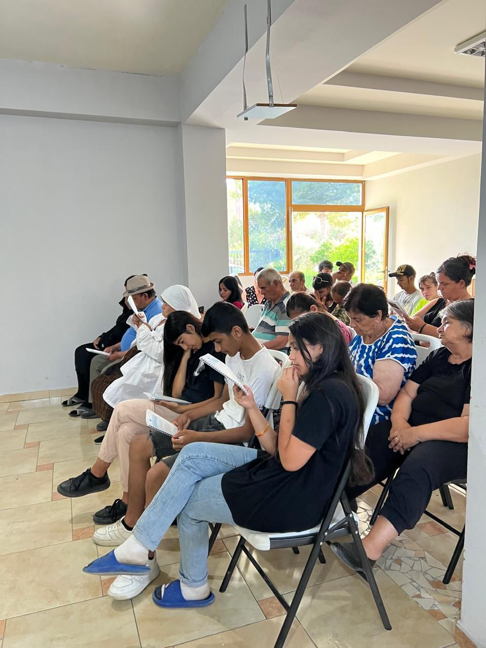 An open book featuring a watercolor painting of daisies with peach and white flowers, sitting on a wooden table in a dimly...
