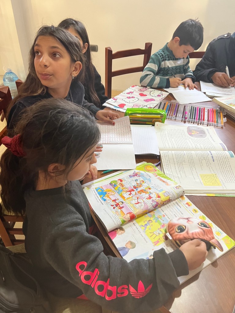 Photo of a woman with a neutral expression, a brown sweater, and black hair, shown from the upper chest up, set against a ...